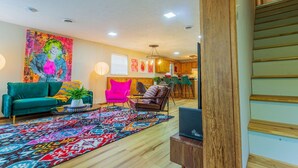 A living room with a green sofa, a pink armchair, and a patterned rug. - ACID WASH @ DOLLYS DRIVE * Wifi Grill Woods Mtns (Sevierville)