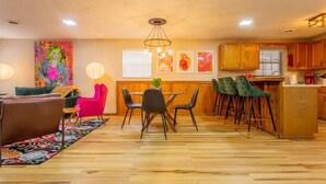 A modern kitchen with wooden cabinets, a dining area with a table and chairs, and a vibrant painting on the wall. - ACID WASH @ DOLLYS DRIVE * Wifi Grill Woods Mtns (Sevierville)