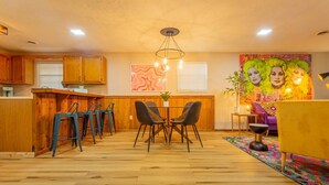 A modern kitchen with wooden cabinets, a bar area, and a dining space with two chairs and a table. - PSYCHEDELIC @ DOLLYS DRIVE * Wifi Grill Woods Mtns (Sevierville)