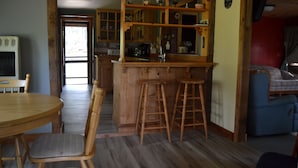 A cozy kitchen with wooden cabinets, a bar stool, and a dining table with chairs.