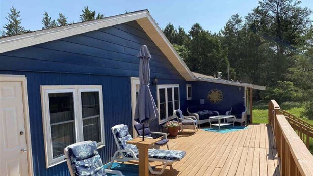 Un bâtiment bleu doté d’une terrasse, de sièges en plein air et d’une piscine.