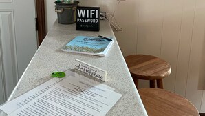 Un comptoir d’accueil avec un calendrier, un panneau indiquant le mot de passe du Wi-Fi, un panneau d’accueil et un livre d’or.