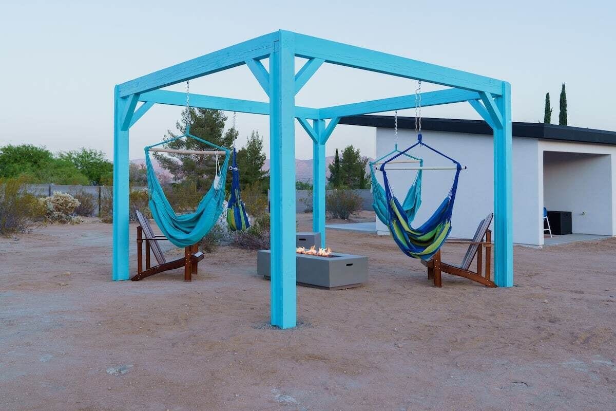 Une structure en bois bleue, avec deux hamacs suspendus.