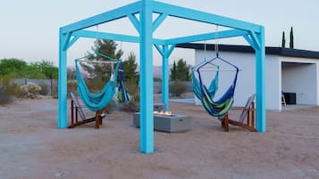 Une structure en bois bleue, avec deux hamacs suspendus.