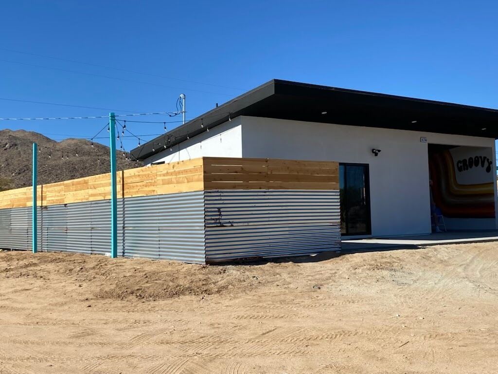 A modern building with a flat roof, a wooden section on the left, and a garage on the right.