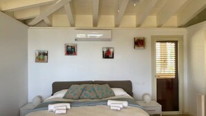 A bedroom with a bed, bedside tables, a ceiling fan, and artwork on the walls. - Sea La Vie Luxury Villa with Panoramic View and Pool (Antigua)