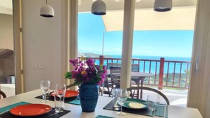 A dining table set with plates, cutlery, and glasses, overlooking a balcony with a view of the sea. - Sea La Vie Luxury Villa with Panoramic View and Pool (Antigua)