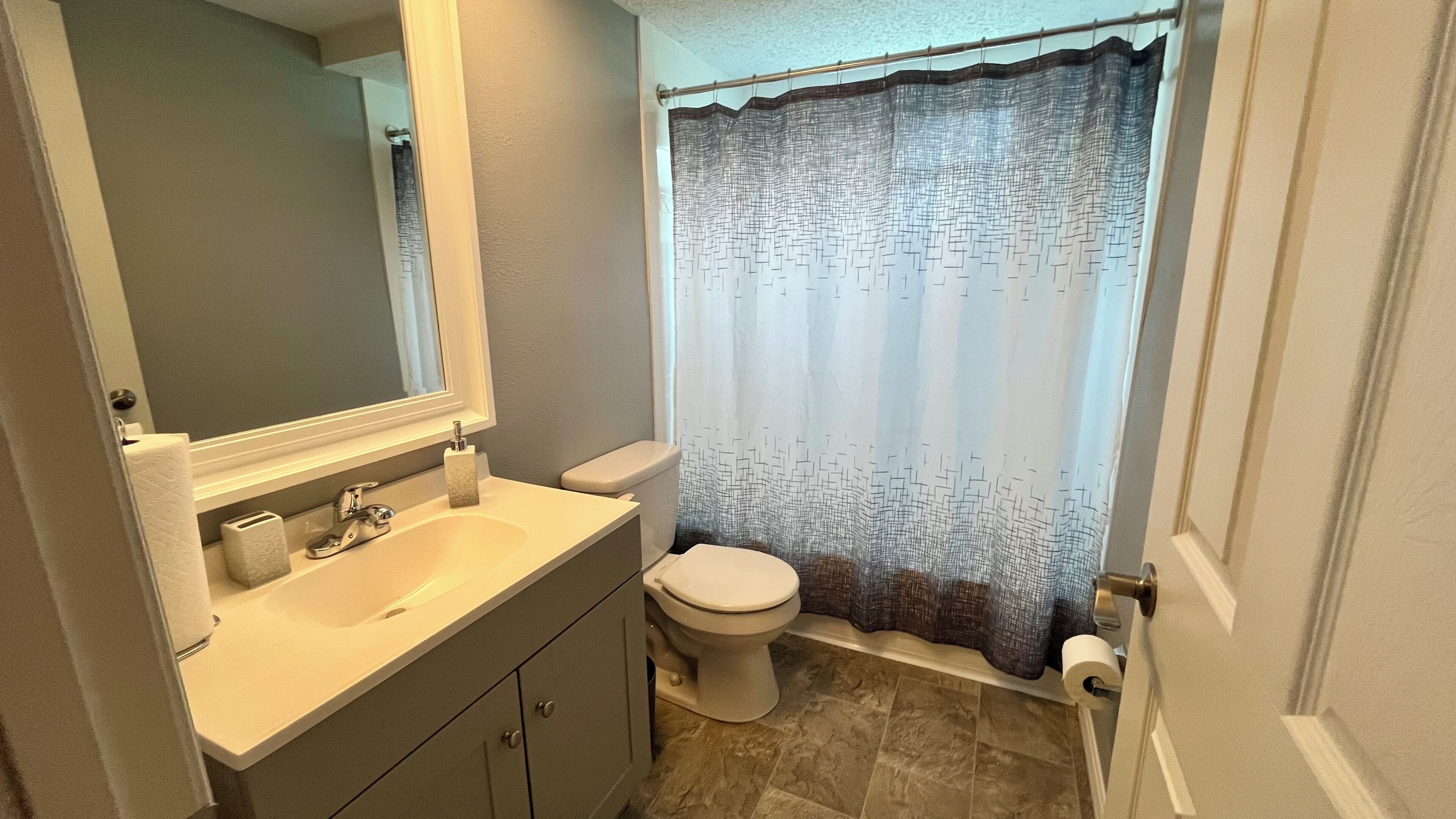 A bathroom with a sink, toilet, and shower curtain.