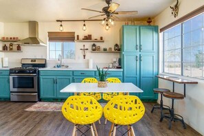 A kitchen with teal cabinets, a white table, and yellow chairs.