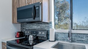 A modern kitchen with a built-in microwave, stove, and sink. - ❤Hot Tub + Close to Downtown JT ❤ Fully Fenced + Firepit Mini❤ (Joshua Tree)