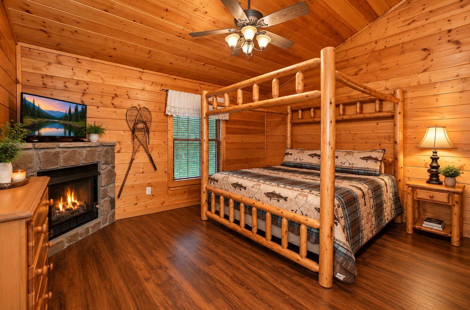 A log cabin bedroom with a four-poster bed, a fireplace, a television, and a ceiling fan.