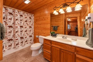 A wooden cabin bathroom with a toilet, sink, and mirror. - ❤Family Friendly❤3 Min to Parkway❤Gameroom, Hot Tub, Theater❤ (Pigeon Forge)