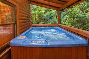 A hot tub in a wooden cabin with a wooden deck and a view of greenery. - ❤Family Friendly❤3 Min to Parkway❤Gameroom, Hot Tub, Theater❤ (Pigeon Forge)