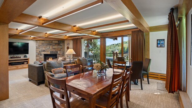 A spacious living room with a fireplace, comfortable seating, a dining area, and large windows offering a view of the outdoors. - Ski-in/ski-out directly from unit, 4 Bdrm DLX, Stonebridge Condos #925 (Snowmass Village)