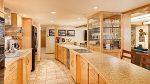 A spacious kitchen with wooden cabinets, a central island, and a glass display case. - Ski-in/ski-out directly from unit, 4 Bdrm DLX, Stonebridge Condos #925 (Snowmass Village)