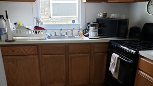 Una cocina con armarios de madera, un fregadero, una estufa y un ventanal.