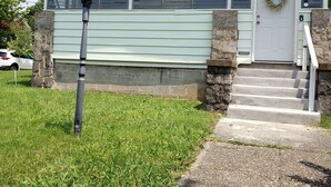 Una casa de dos pisos con un porche delantero, pilares de piedra y una puerta principal adornada con un adorno.
