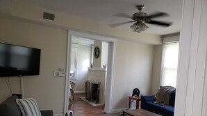 Una sala de estar con televisor, sofá, reposapiés y chimenea.
