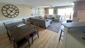 Ein geräumiges Wohnzimmer mit einem großen Esstisch, einer Couch und einem gemusterten Sessel.