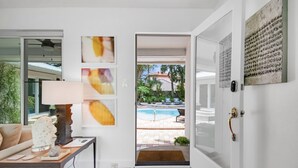 Un salon moderne avec un canapé, une table basse agrémentée d’objets décoratifs, une lampe et une vue sur une piscine extérieure.