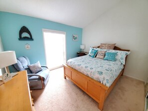 A bedroom with a bed, a chair, a desk, and a door. - Headline (St. Augustine)