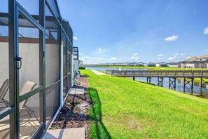 Een modern gebouw met grote glasramen, een gazon en een houten brug over water.