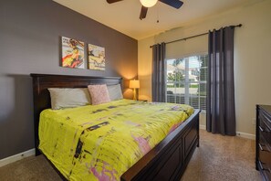 Un dormitorio con cama, ventilador de techo, ventana con cortinas y una obra de arte en la pared.