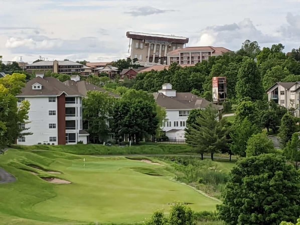 A golf course with a clubhouse, surrounded by residential buildings and trees.