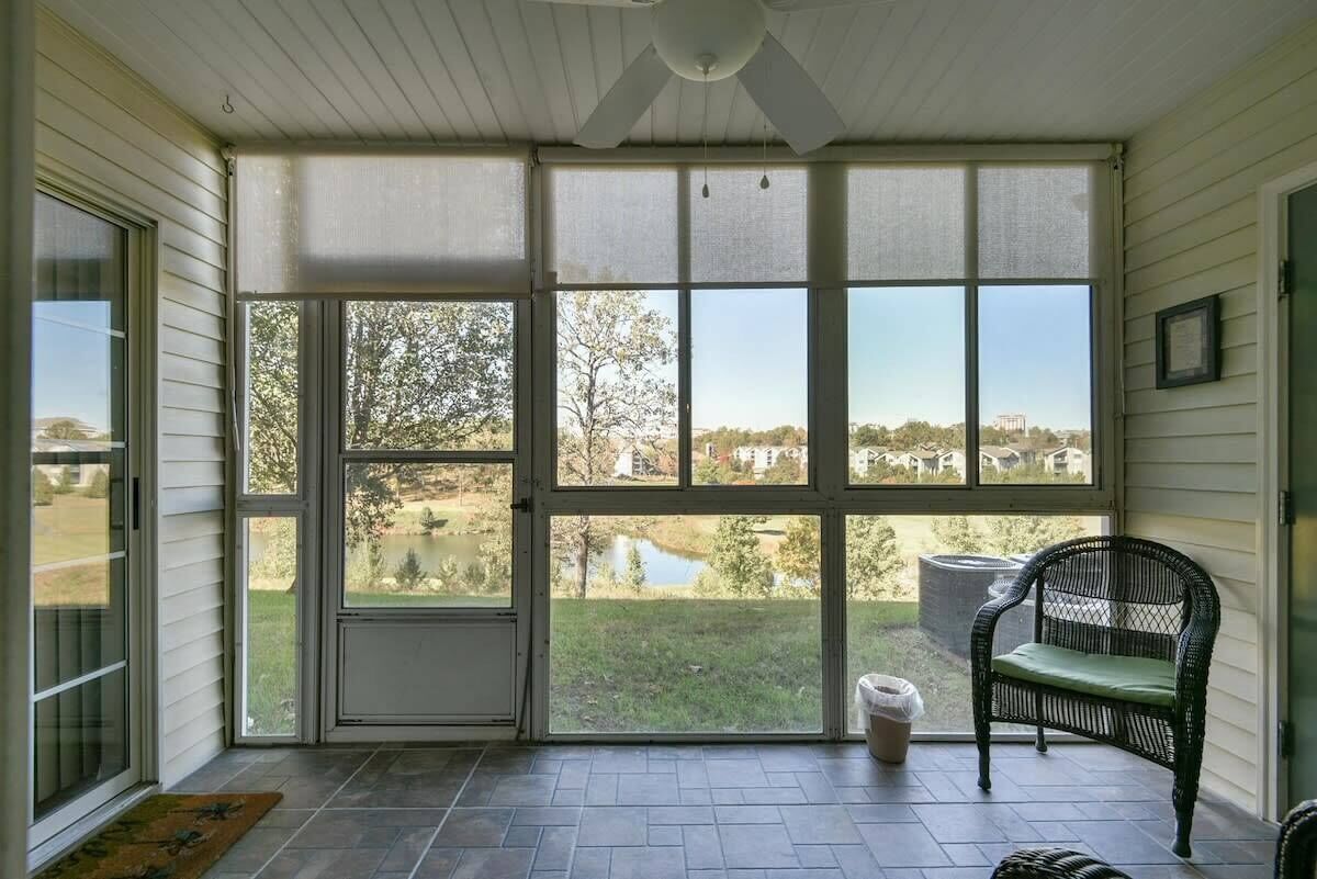 A covered porch with a view of a lake and houses.