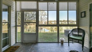 En overdækket veranda med udsigt til et sø og huse.