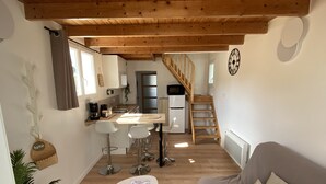 Un espacio habitable compacto con cocina, comedor y una escalera que lleva a un nivel superior.