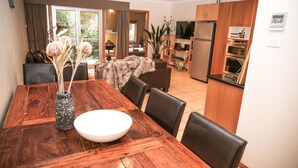 Ein Essbereich mit einem Holztisch, Stühlen und einer Vase mit Trockenblumen.