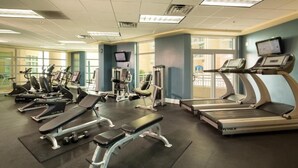 Ein Fitnessstudio mit Laufbändern, Crosstrainern und Gewichtsbänken.