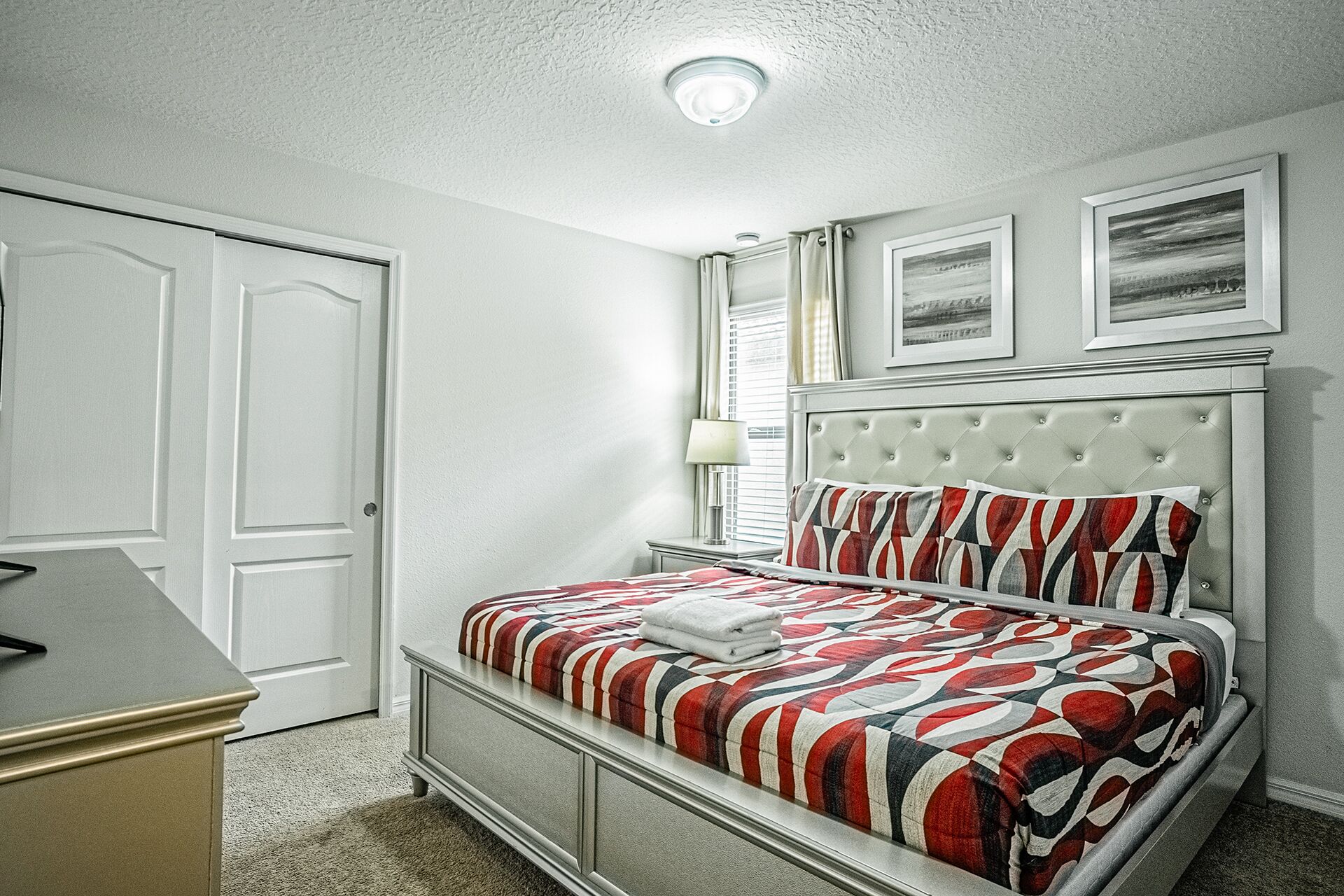 Una camera da letto con un letto, un comodino, una lampada e una porta.