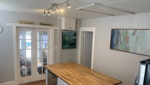 A kitchen with a wooden countertop, white cabinets, and a view of the outdoors through a glass door. - This bungalow is 5 min from downtown the riverfront and 12 min from the beach! (wilmington)