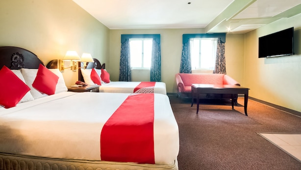 Quarto de hotel com duas camas, uma escrivaninha, uma cadeira e uma televisão.
