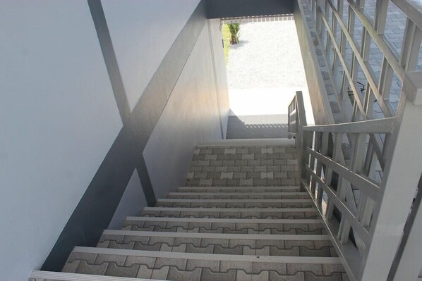 A staircase with a geometric pattern on the steps, leading to a bright outdoor area. - Charin Village (Chalong)