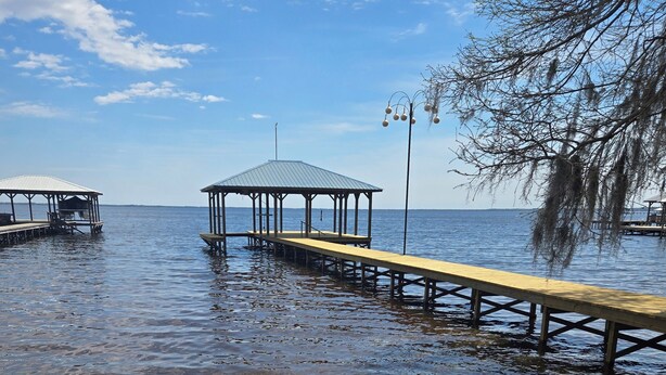 A beach with wooden walkways leading to covered structures over water. - Pappy's Pool Lake: A  1650 sqft with Pier,  Boat Ramp, Screened porch,Lakeside. (Lake Waccamaw)