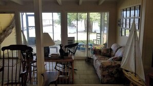 A cozy living room with a sofa, chairs, a table, and a hammock. - Pappy's Pool Lake: A  1650 sqft with Pier,  Boat Ramp, Screened porch,Lakeside. (Lake Waccamaw)