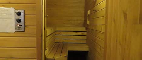 Uma sauna com bancos de madeira e um painel de controle na parede.