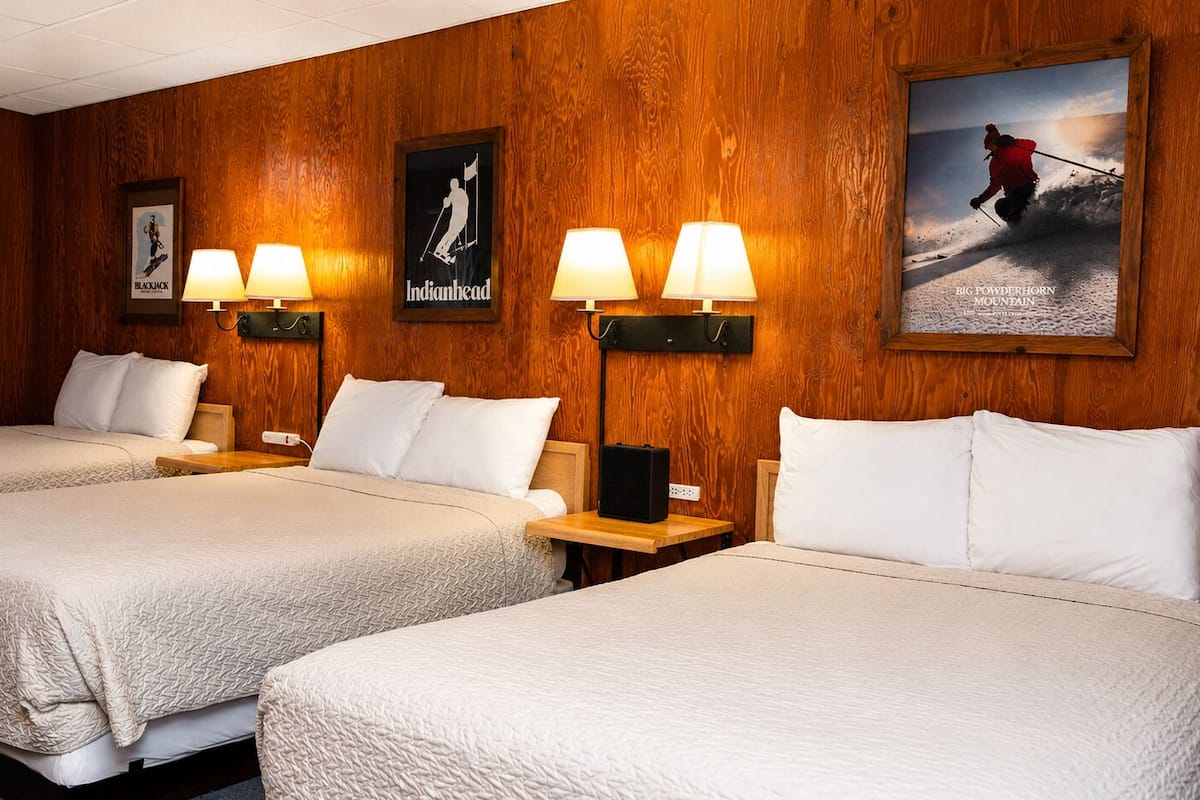 Ein Hotelzimmer mit zwei Betten, Holzwandverkleidung und Wandlampen.