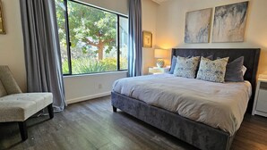 A bedroom with a large bed, two bedside tables, a chair, and a window with curtains. - Modern Condo in Gated Silverado Resort Residential Community (Napa)