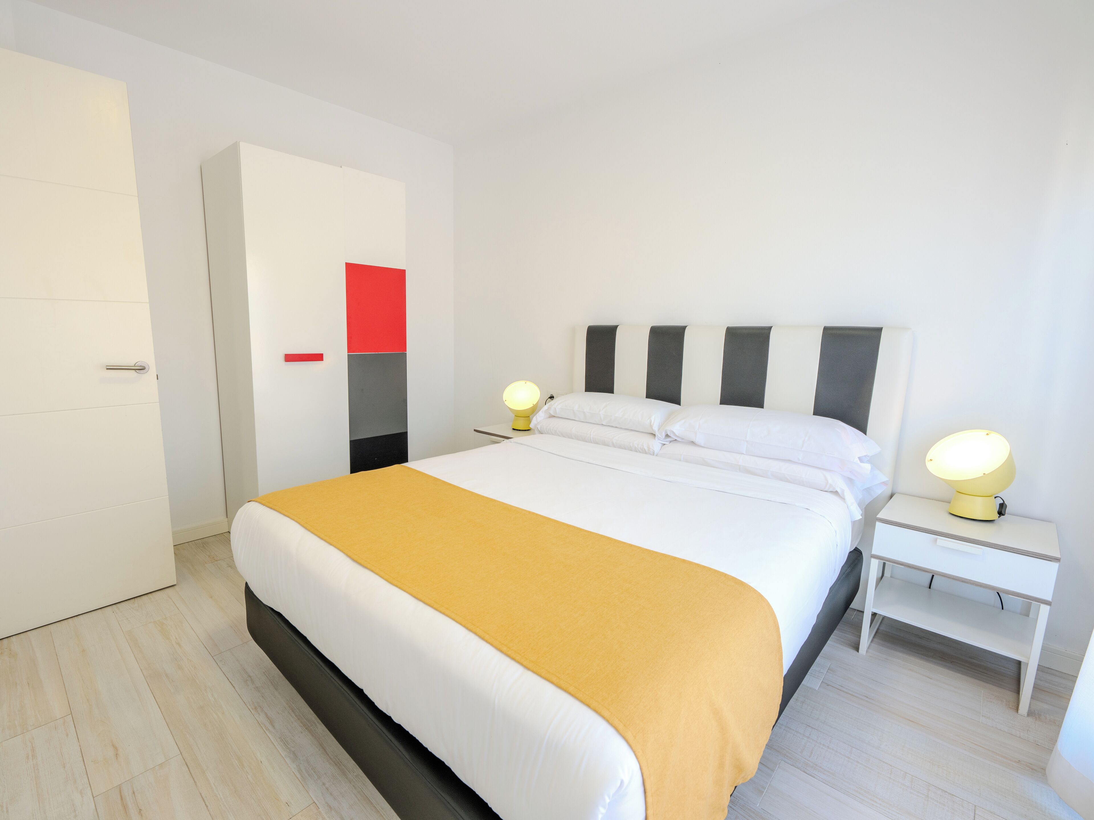 A modern bedroom with a bed, bedside tables, and a wardrobe.