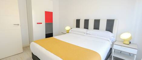 A modern bedroom with a bed, bedside tables, and a wardrobe.
