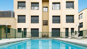 Una piscina al aire libre de temporada, sillones reclinables de piscina