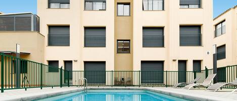 Een seizoensgebonden buitenzwembad, ligstoelen bij het zwembad