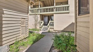 A residential building with a covered outdoor staircase, a garage, and a small garden area. - Cozy Family Condo in Mammoth Lakes w/ Balcony (Mammoth Lakes)