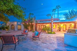 A patio area with outdoor seating, a grill, and a building with a tiled roof and arched windows. - Tranquil Acre Oasis, Waterslide Heated Pool, Firepit, Spacious Backyard Estate (Scottsdale)