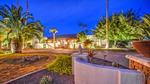 A well-maintained garden with palm trees, a stone pathway, and a large planter. - Tranquil Acre Oasis, Waterslide Heated Pool, Firepit, Spacious Backyard Estate (Scottsdale)