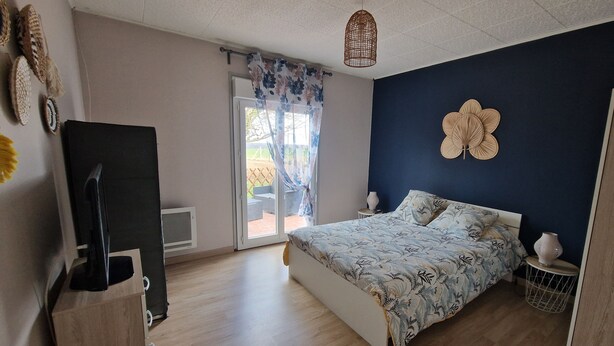 Une chambre à coucher avec un lit, une télévision, une fenêtre avec des rideaux et une porte.